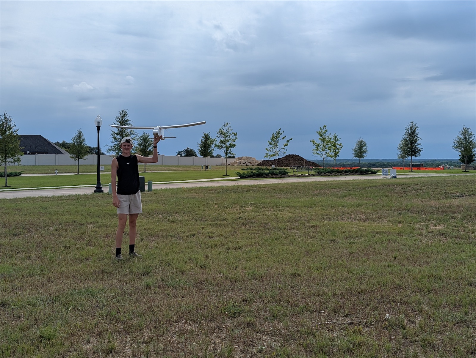 A member standing in a field holding the plane overhead
