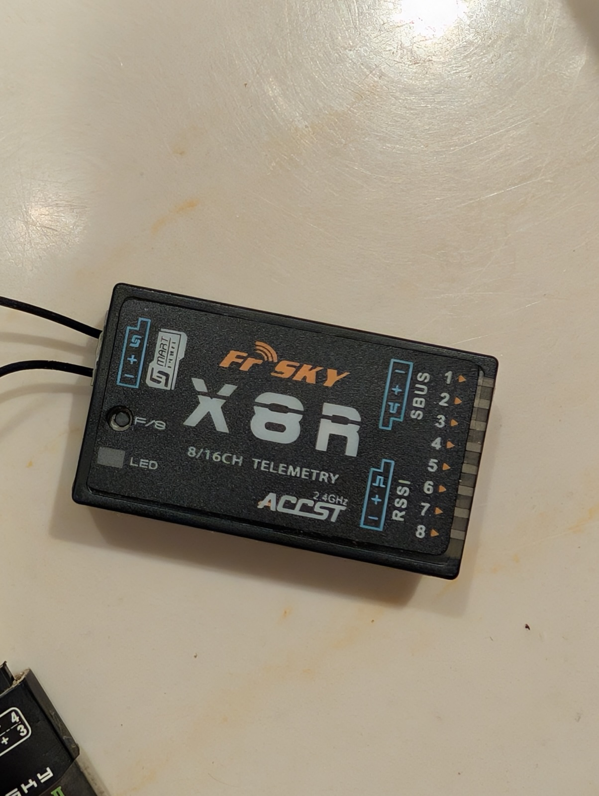 Close-up of a black FrSky X8R radio receiver with its antenna leads