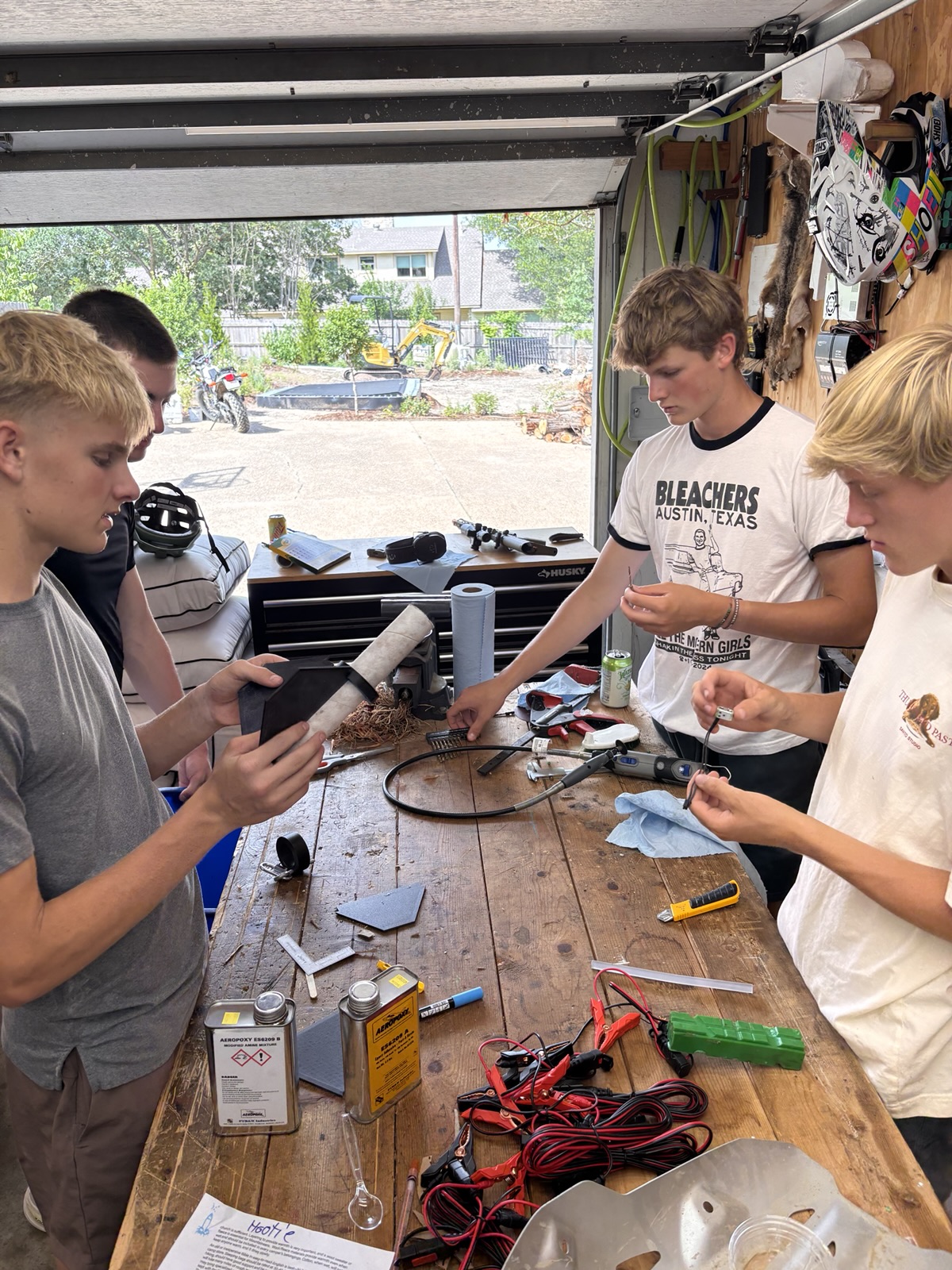 Members fitting black 3D-printed fins to the rocket body tube at a workbench