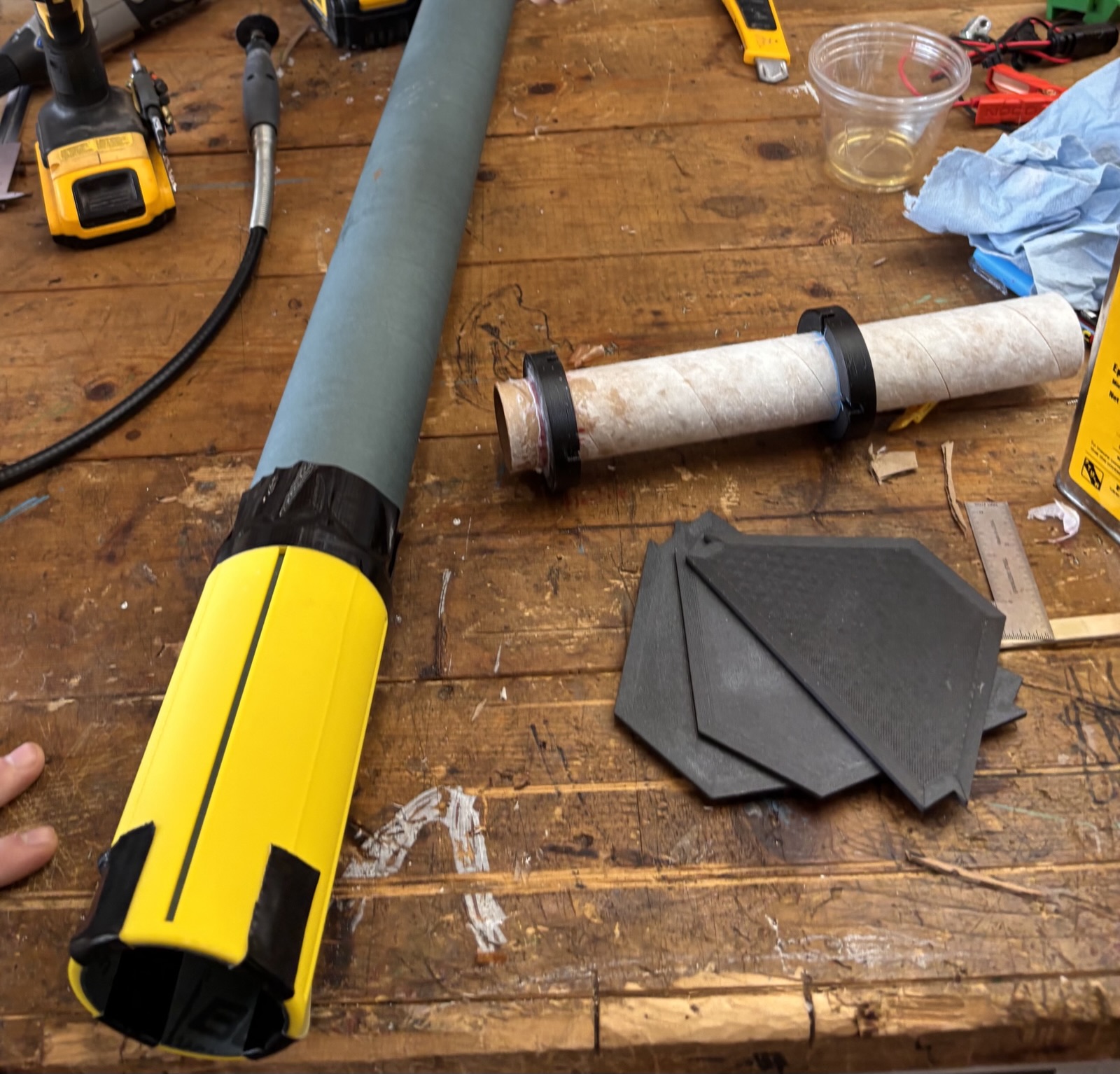 Blue Tube airframe in a yellow 3D-printed slot-cutting jig next to the motor mount and fins