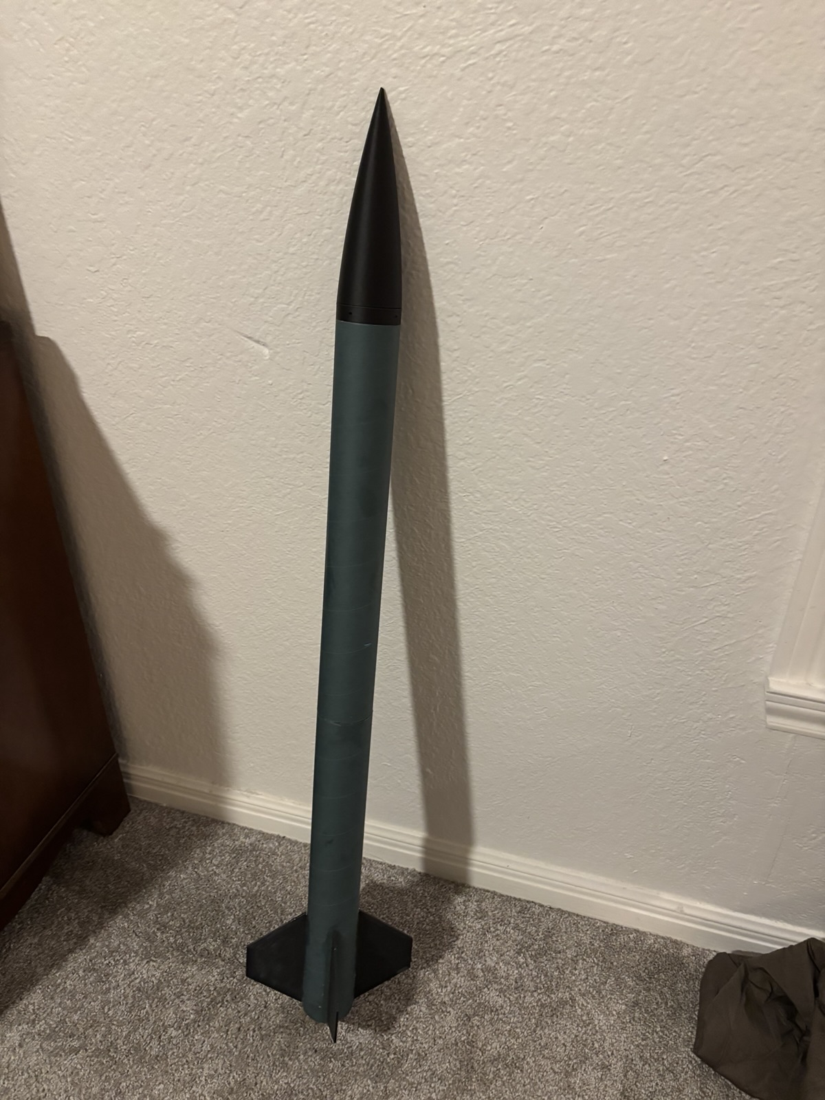 The rocket in progress, with a black nose cone and blue airframe, standing upright