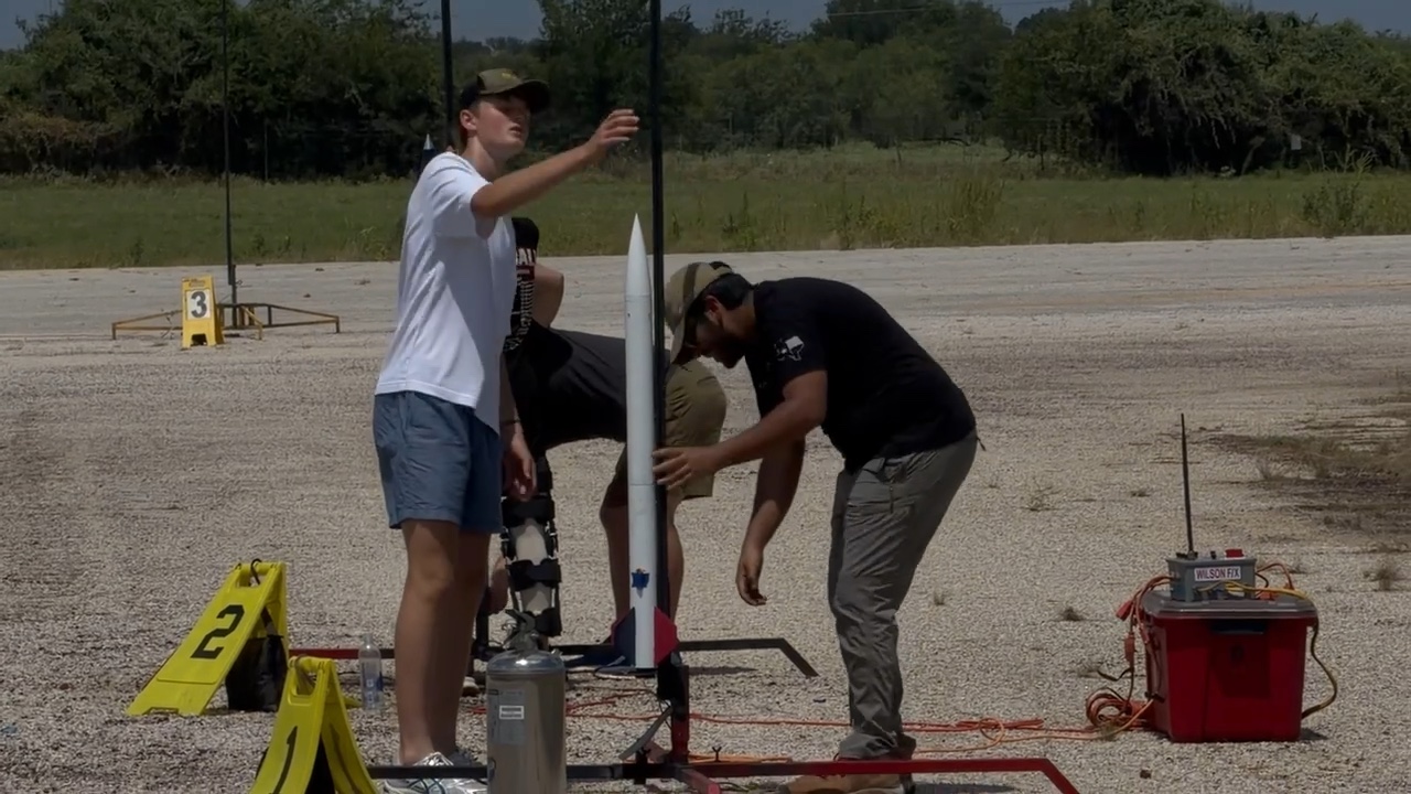A member and a range volunteer raising the launch rail with the rocket mounted on it